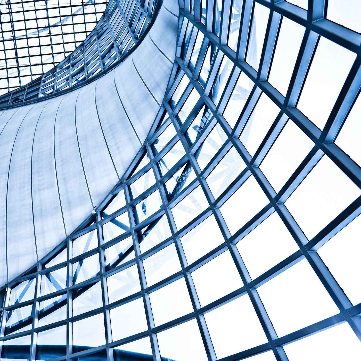Vista de arquitectura moderna en vidrio y acero con tonos azules, representando la plataforma global de Newmark